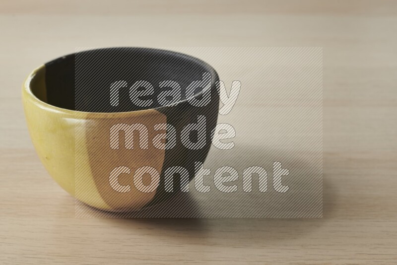 وعاء فخاري متعدد الألوان على خلفية خشبية فاتحة