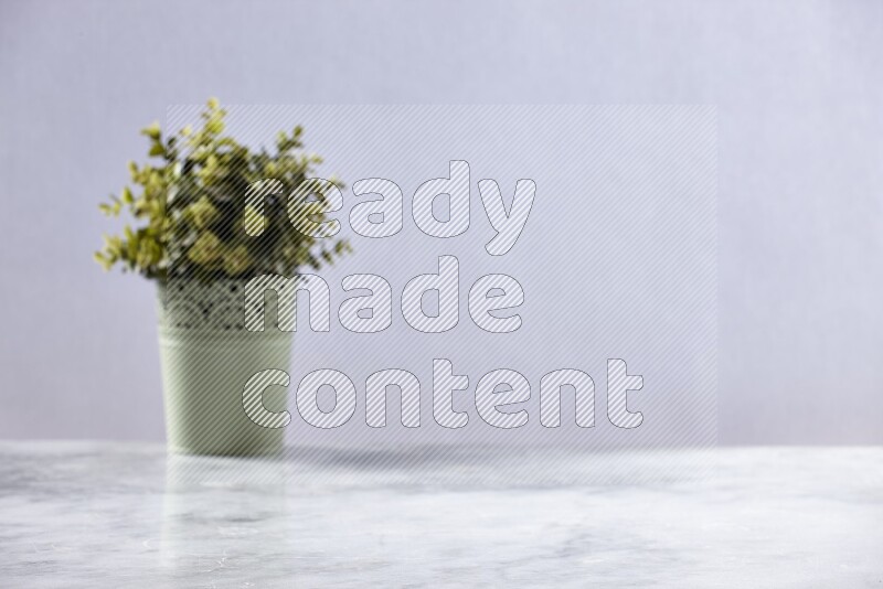 Artificial plant in green decorative pot on grey marble background