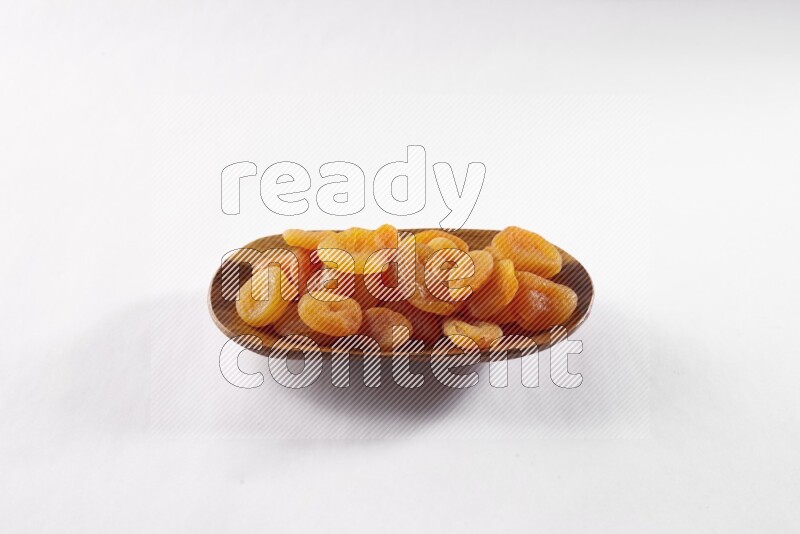 Dried apricots in a wooden plate on white background
