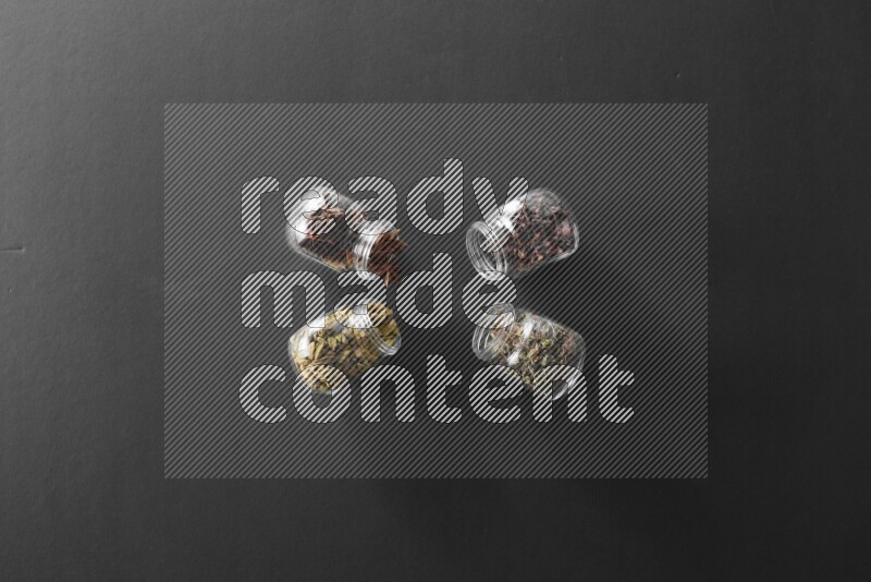 قرنفل وحبوب الهيل وريحان مجفف ويانسون نجمي في أوعية زجاجية علي خلفية سوداء