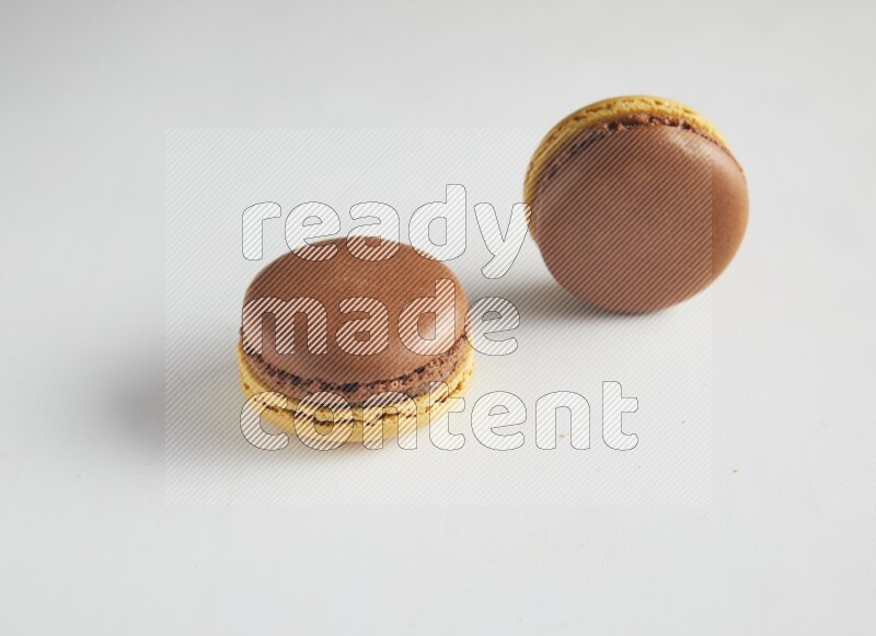 45º Shot of two Yellow and Brown Chai Latte macarons on white background