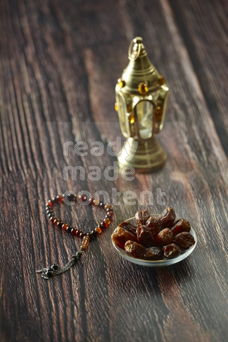 A golden lantern with different drinks, dates, nuts, prayer beads and quran on brown wooden background