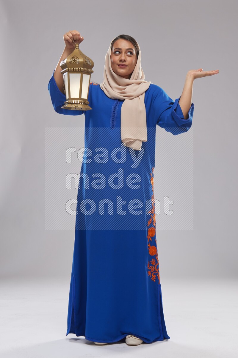 A Saudi woman standing wearing Jalabeya holding a lantern