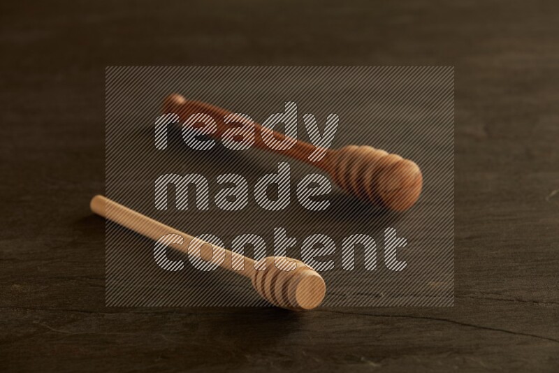 Wooden honey dipper on black slate background