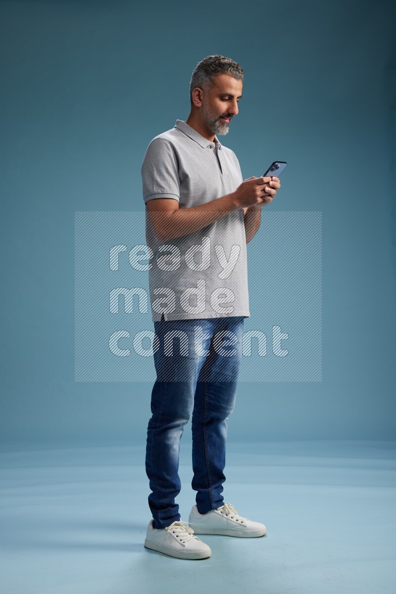 Man Standing texting on phone on blue background