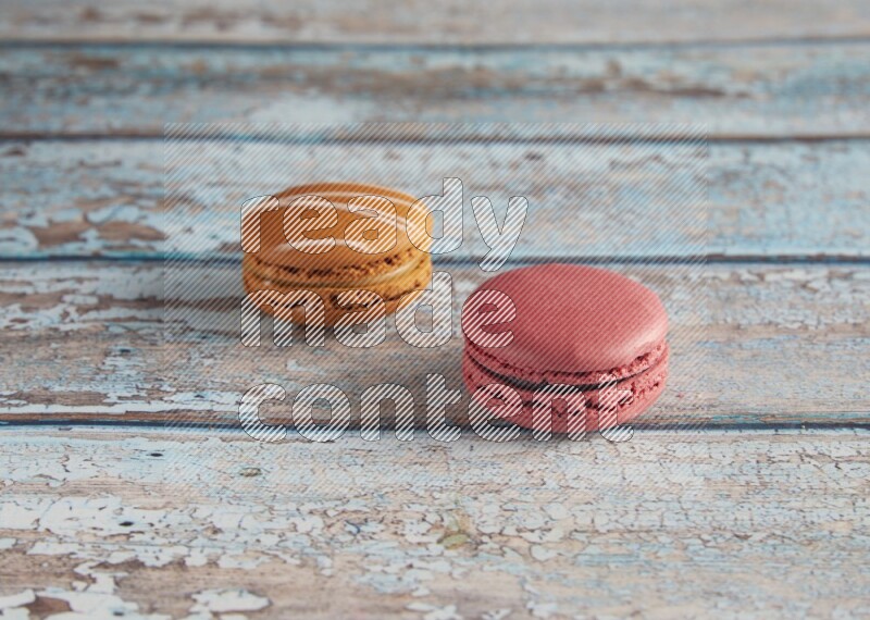 45º Shot of of two assorted Brown Irish Cream, and Pink Raspberry macarons on light blue background