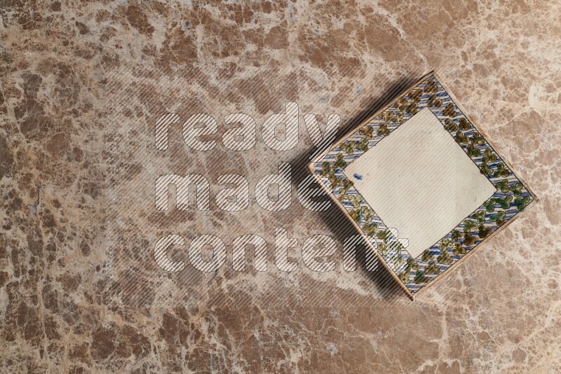 A decorative pottery plate on beige marble background