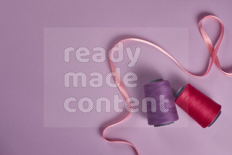 A pink and purple collection of sewing and tailoring tools arranged on a purple background