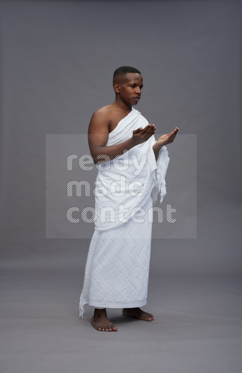 A man wearing Ehram Standing dua'a on gray background