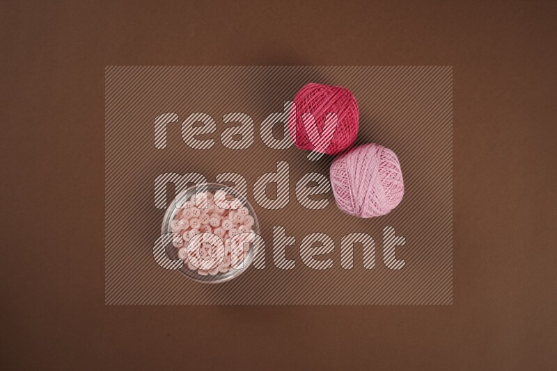 A pink collection of sewing and tailoring tools arranged on a brown background