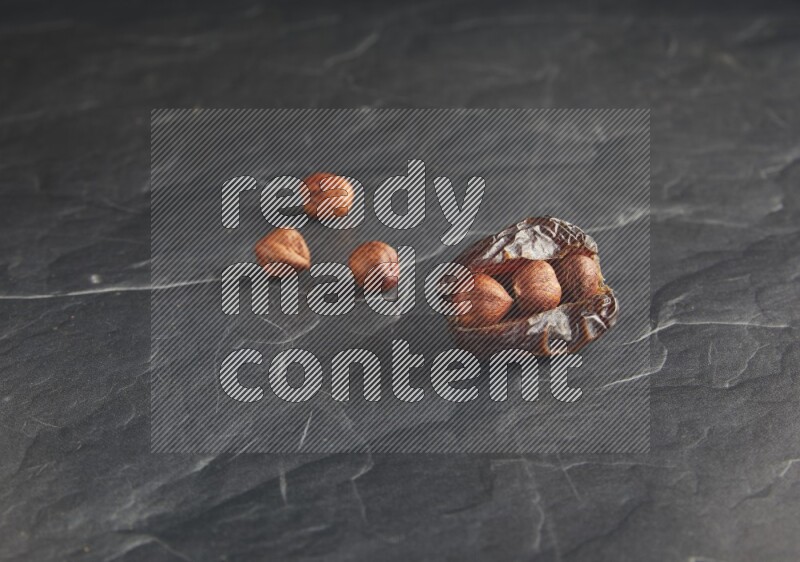 hazelnuts stuffed madjoul date on a black textured background