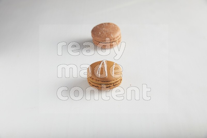 45º Shot of of two assorted Brown Irish Cream, and Brown Hazelnuts macarons on white background