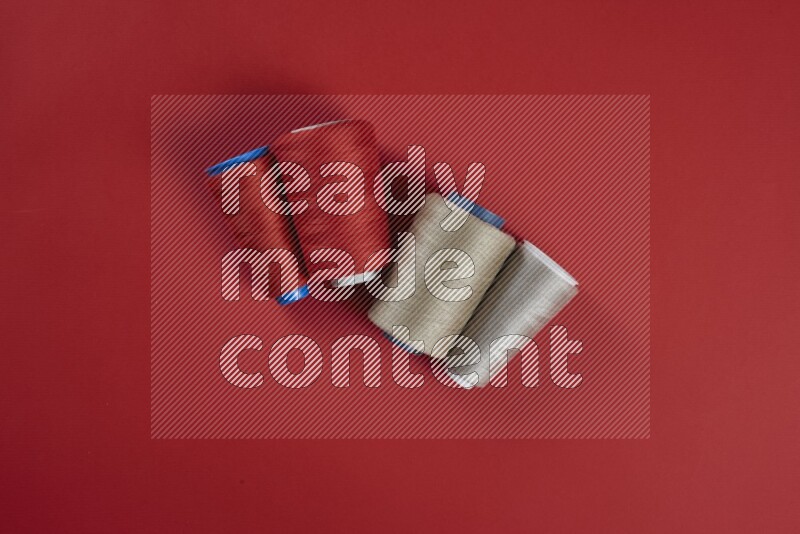 مجموعة من أدوات الخياطة والتفصيل بنية وحمراء اللون على خلفية حمراء