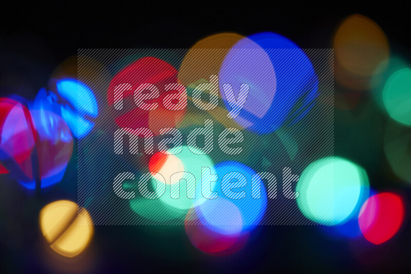 Light bulbs glowing against backdrop of multicolord bokeh