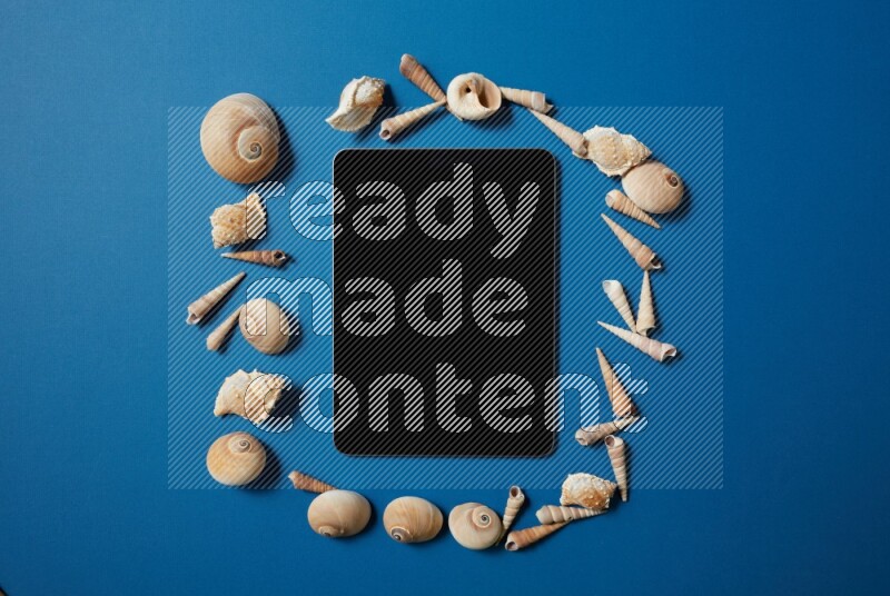 top view shot of a tablet, and seashells on blue background