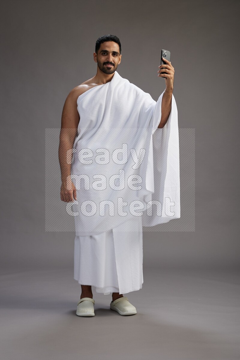 A man wearing Ehram Standing taking selfie on gray background