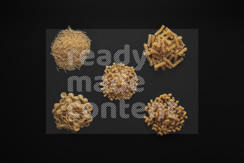 Different pasta types in bunches on black background