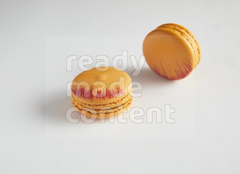 45º Shot of two orange Exotic macarons on white background