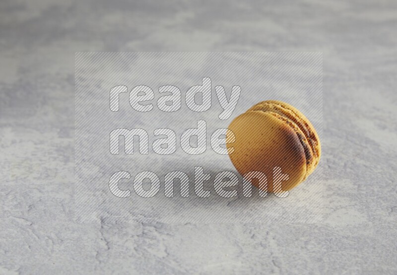 45º Shot of Yellow Crème Brulée macaron on white marble