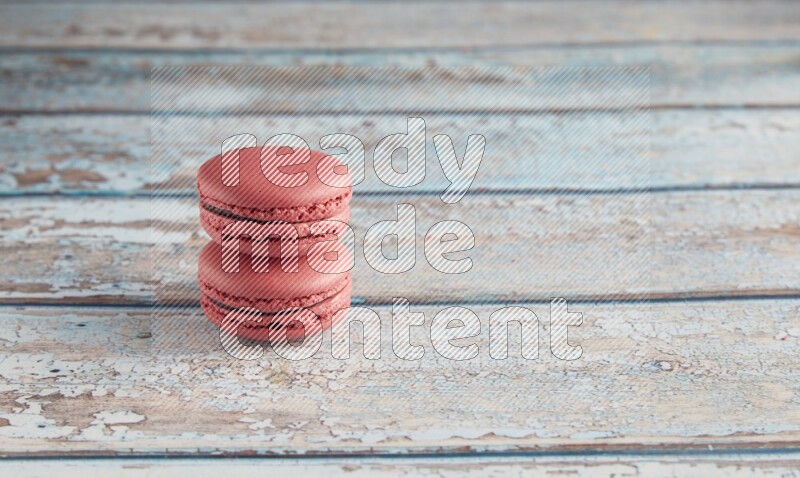 45º Shot of two Pink Raspberry macarons on light blue wooden background