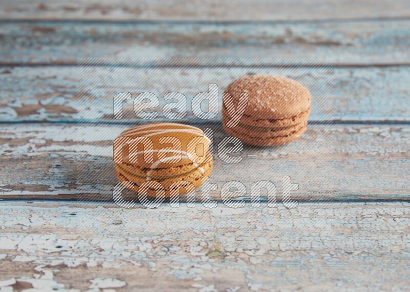 45º Shot of of two assorted Brown Irish Cream, and Brown Hazelnuts macarons  on light blue background