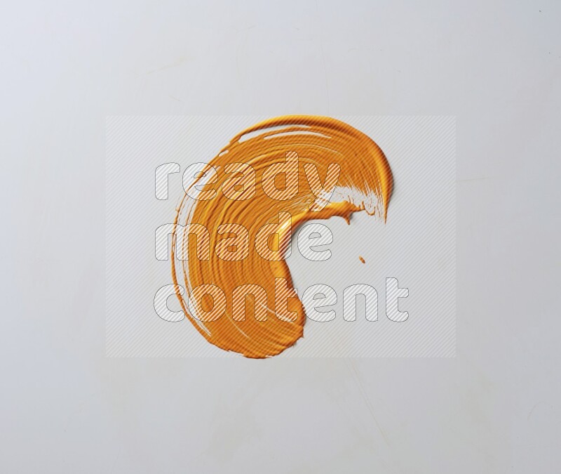 An orange curved painting brush stroke on a white background
