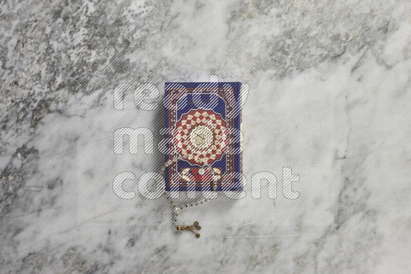 Quran with a prayer beads on grey marble background