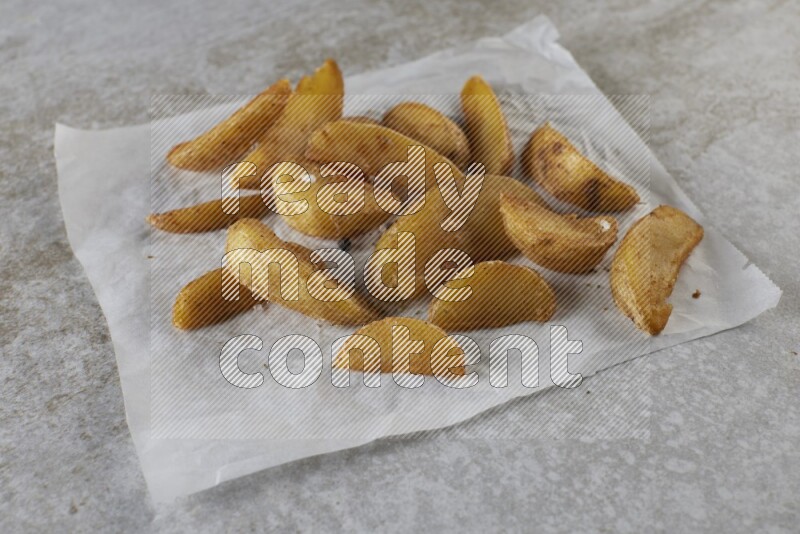 wedges potato on parchment paper on grey textured counter top