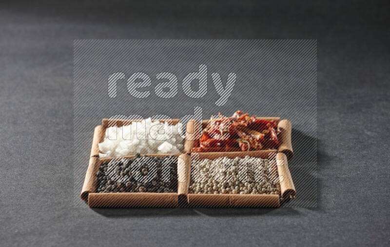 4 squares of cinnamon sticks full of black pepper, white pepper, dried red chilis and white salt on black flooring