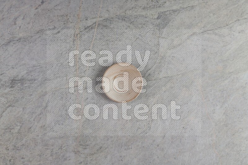 A circular beige pottery plate on grey marble background