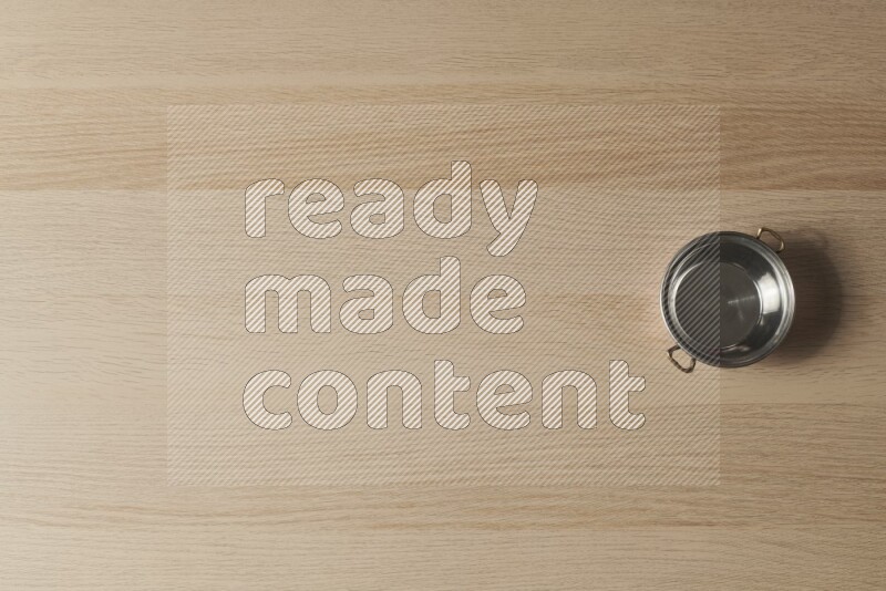 A small copper pot on light wooden background