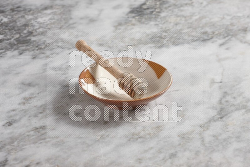 Multicolored pottery plate with wooden honey dipper in it on grey marble background