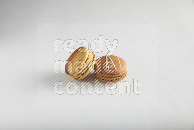 45º Shot of of two assorted Brown Irish Cream, and Yellow Crème Brulée macarons on white background