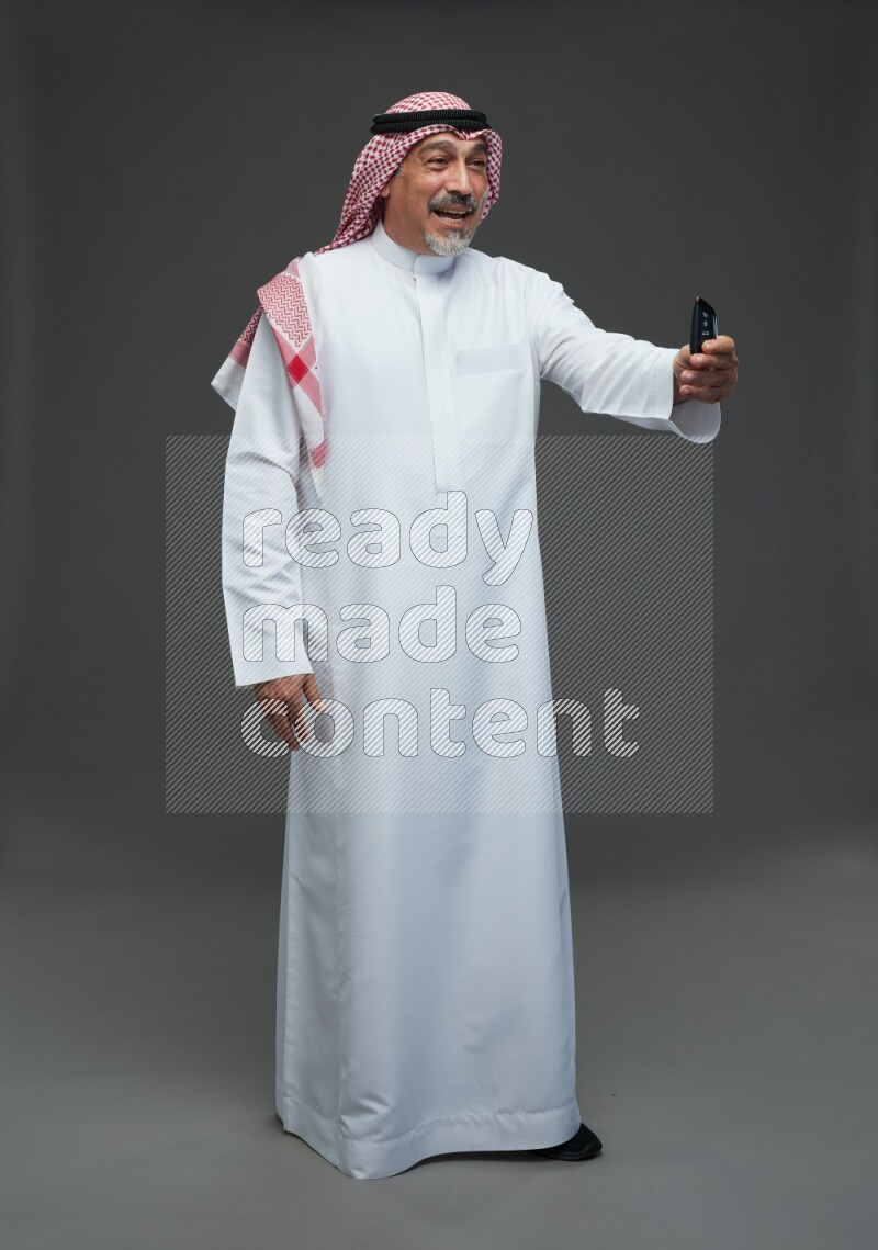 Saudi man with shomag Standing holding car key on gray background