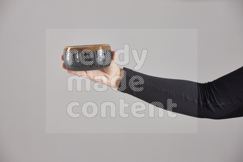 A woman in black abaya holding different pottery essentials in different positions