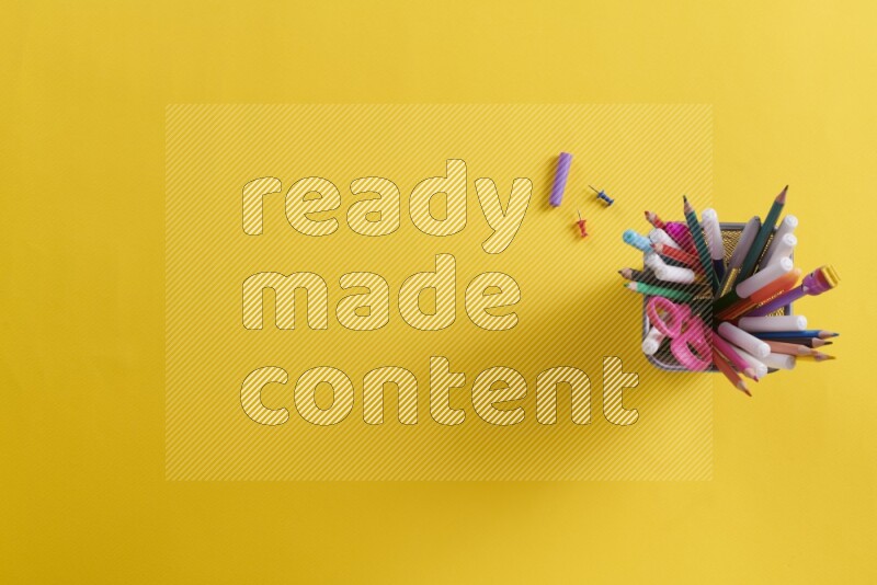 بعض الأقلام والمستلزمات المدرسية في مقلمة معدنية علي خلفية صفراء