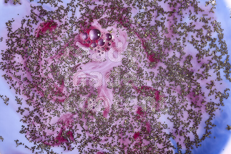 A close-up of sparkling gold glitter scattered on swirling blue and red background