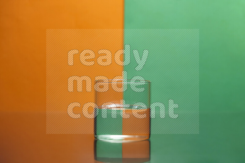 The image features a clear glassware filled with water, set against orange and green background