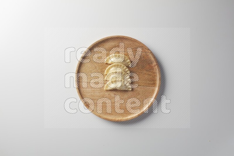 Four Sambosas on a wooden round plate on a white background