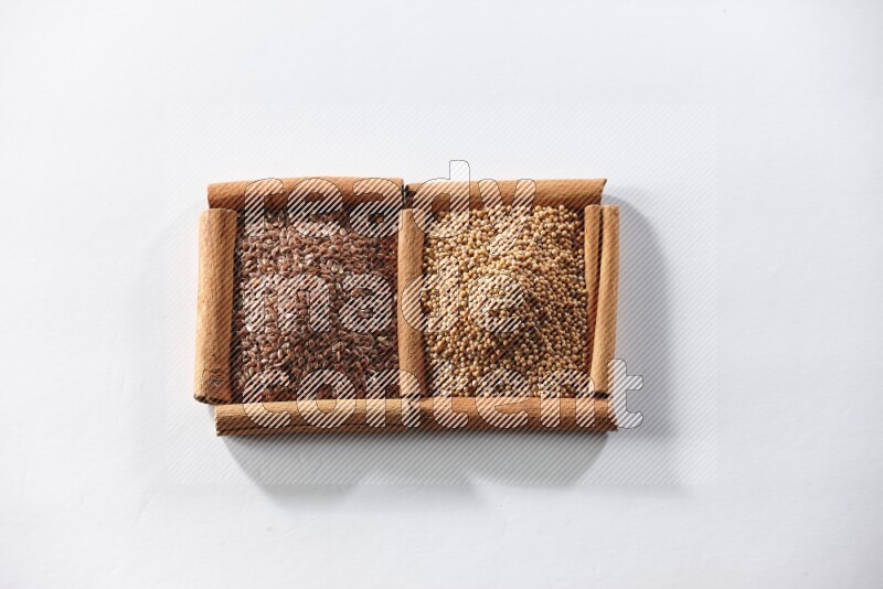 2 squares of cinnamon sticks full of mustard seeds and flaxseeds on white flooring