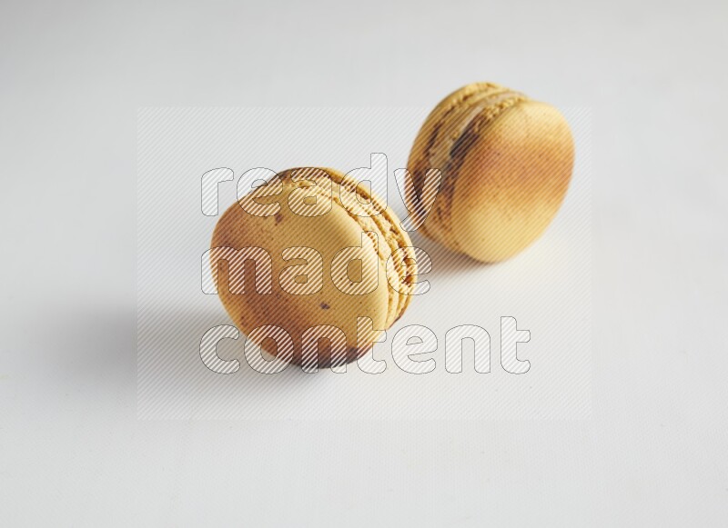 45º Shot of two Yellow Crème Brulée macarons on white background