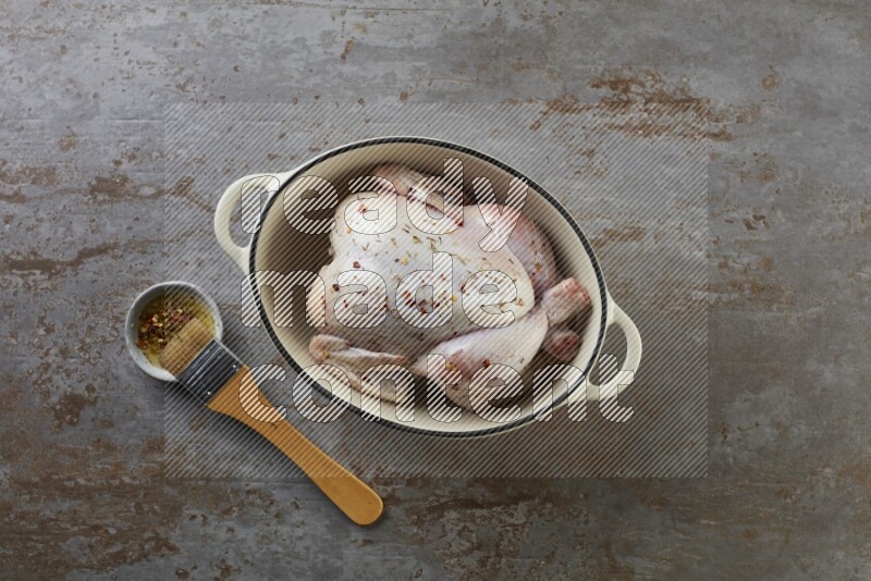 whole raw chicken on in a white ceramic pot direct on a rustic grey background