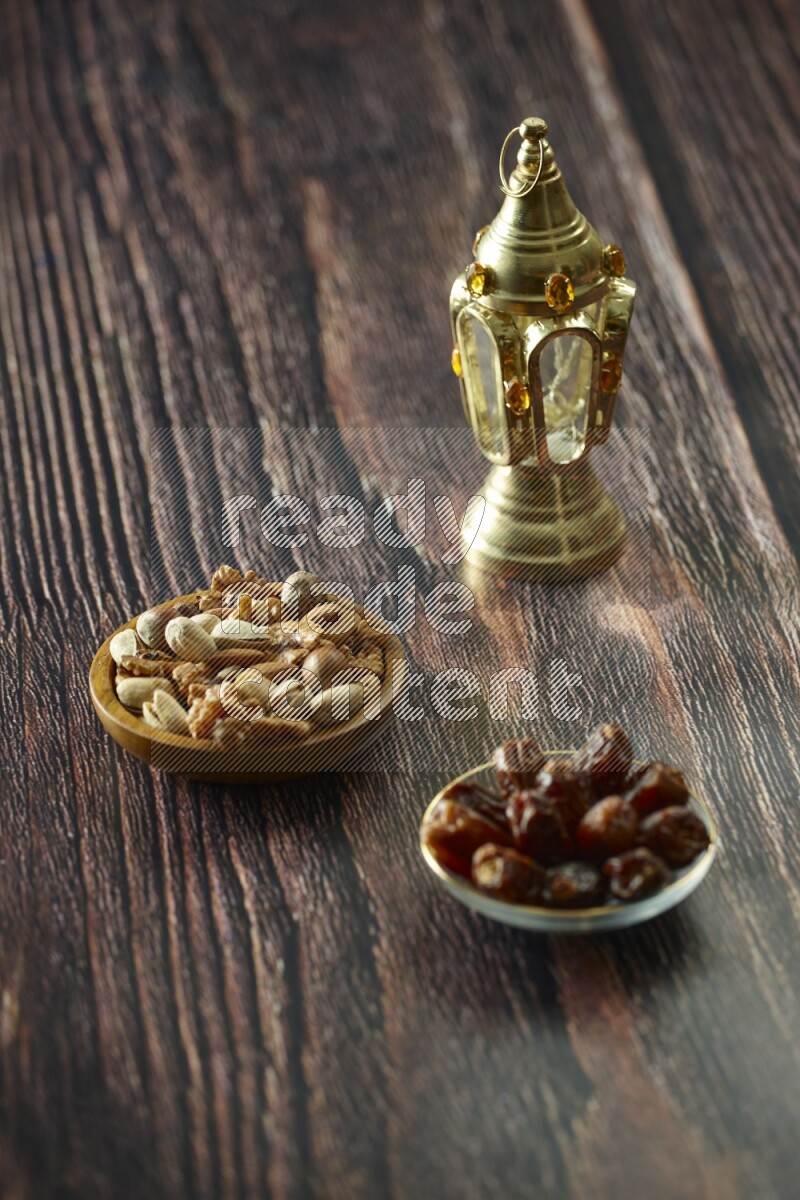 A golden lantern with different drinks, dates, nuts, prayer beads and quran on brown wooden background