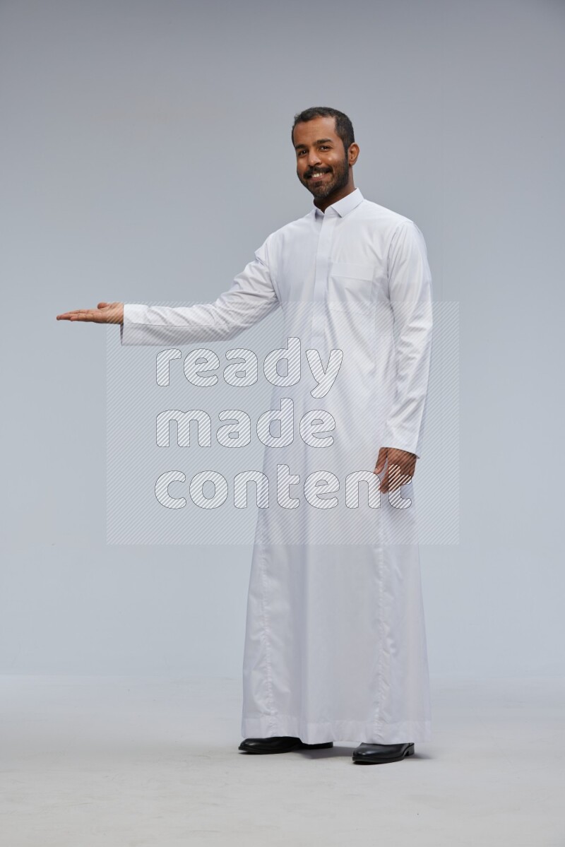 Saudi man Wearing Thob standing interacting with the camera on Gray background