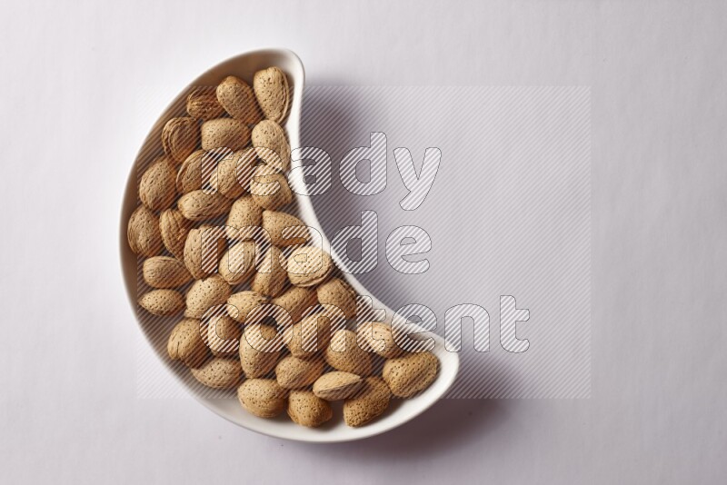 Almonds in a crescent pottery plate on white background