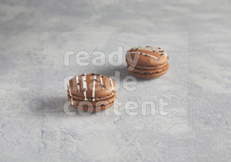 45º Shot of two Brown white marbleChocolate Caramel macarons  on white  marble background