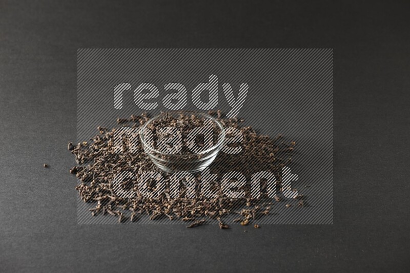 A glass bowl full of cloves on a black flooring