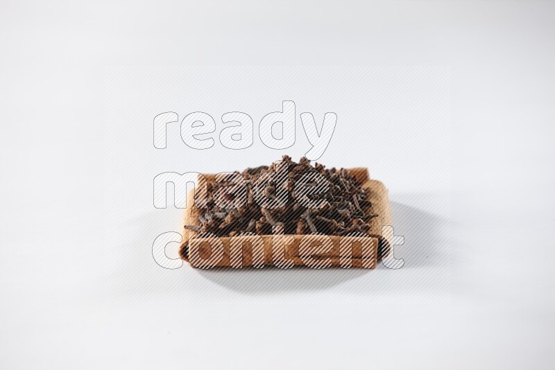 A single square of cinnamon sticks full of cloves on white flooring