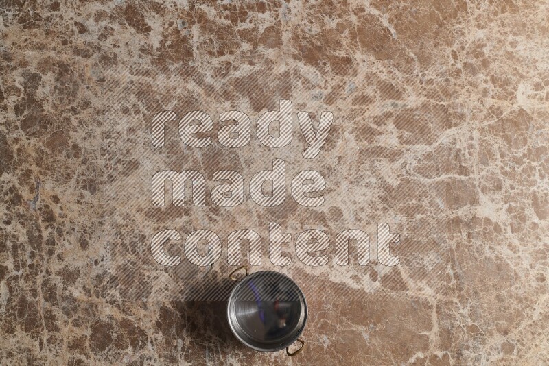A small copper pot on beige marble background
