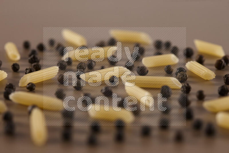 معكرونة مع مكونات متنوعة من الطماطم والثوم والبصل والفلفل الأحمر والفلفل الأسود والفلفل الأبيض وأوراق الغار وإكليل الجبل والهيل على خلفية بيج